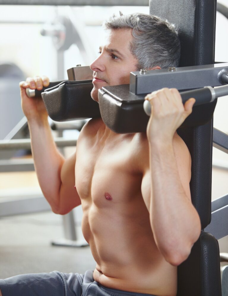 Broadening his shoulders. A mature man working out on equipment at the gym.