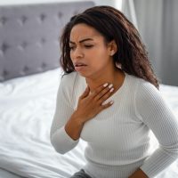 Young black woman coughing, suffering from sore throat
